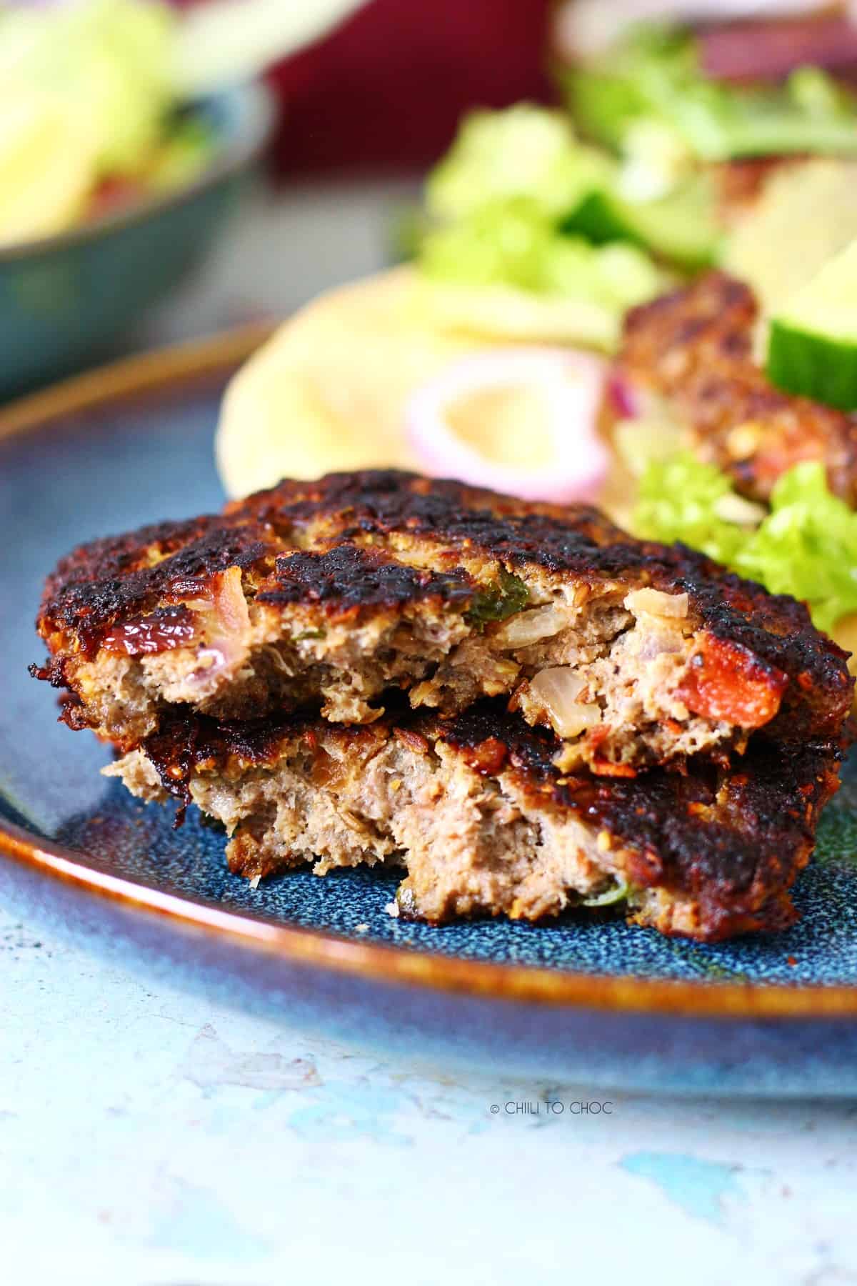 A chapli kabab broken into two on a blue plate.