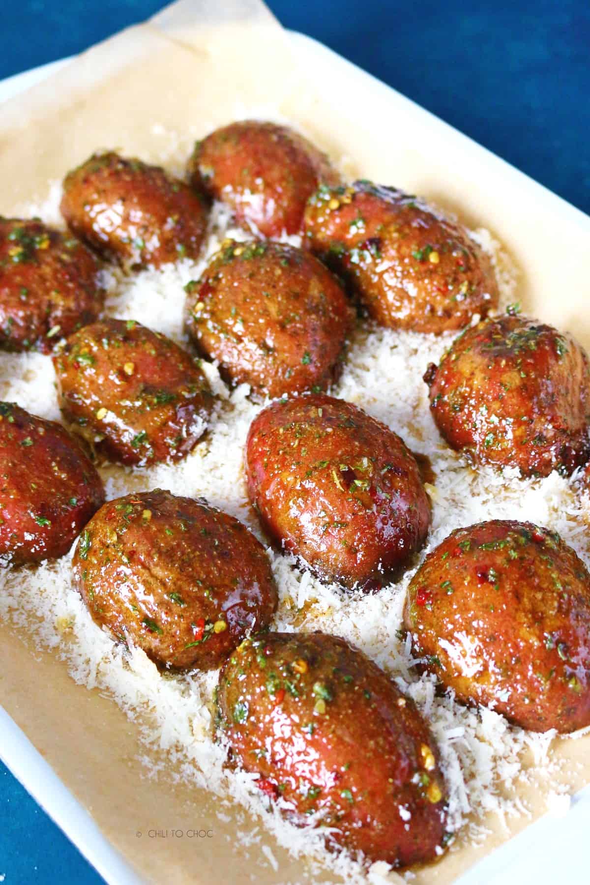 Seasoned potato halves on a bed of grated Parmesan.