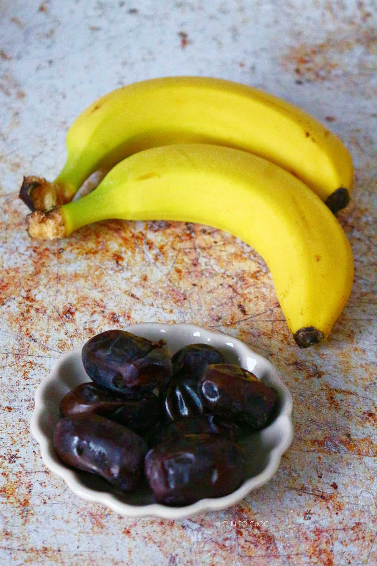 Dates in a small plate and two bananas at the back.