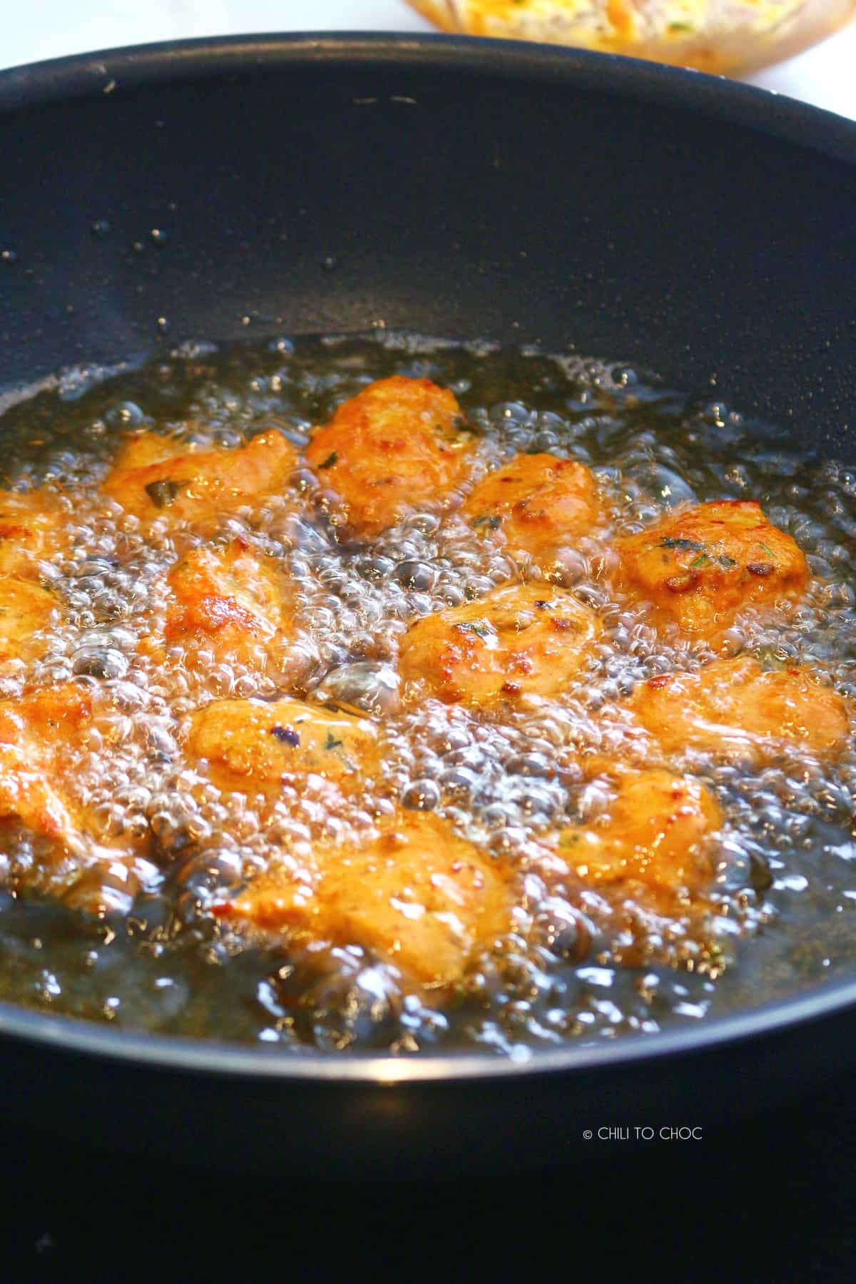 Deep frying fish fritters in a wok.