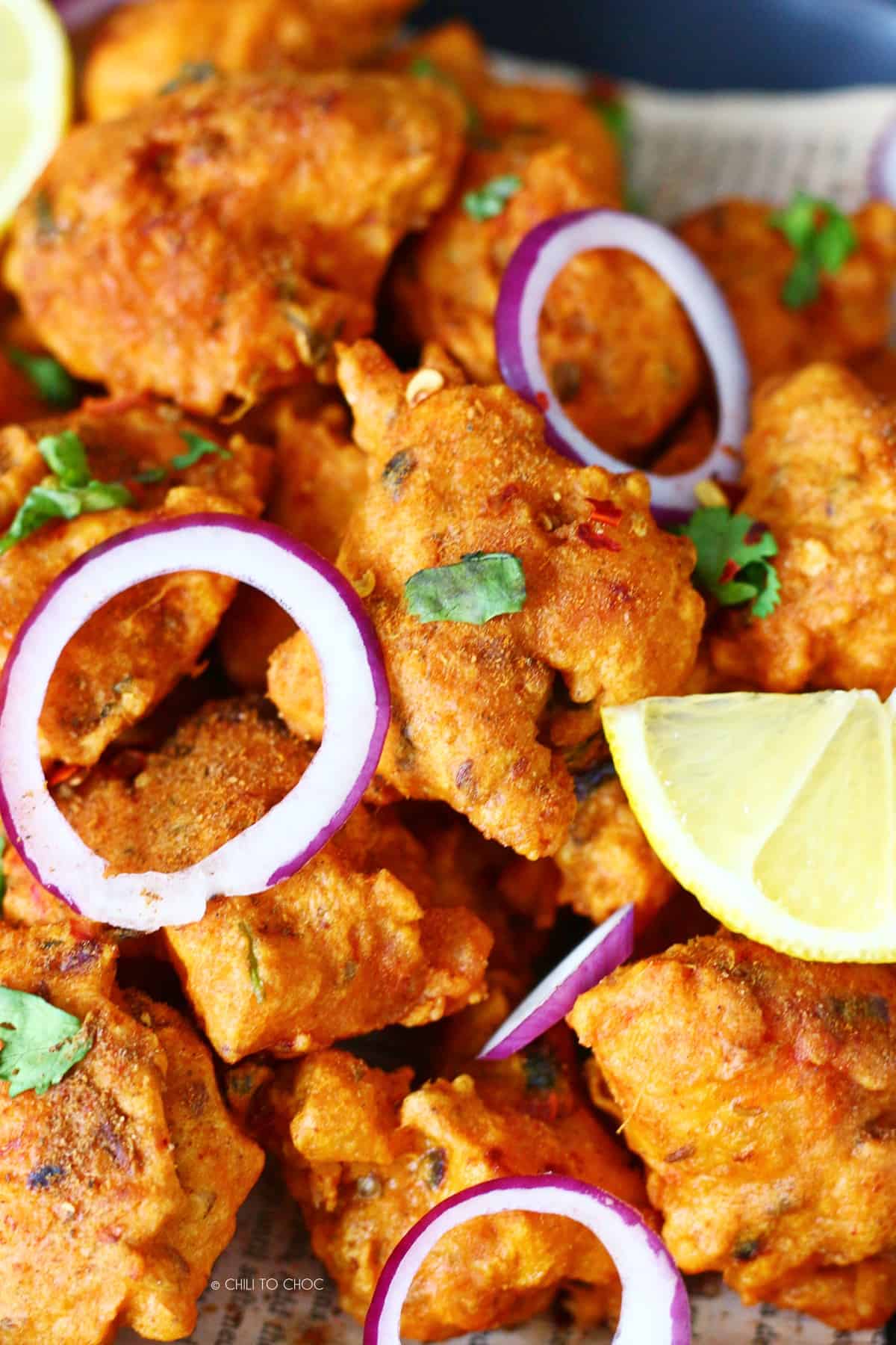 Fish pakora with onion rings and lemon wedges.