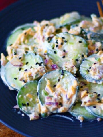 Jalapeno Popper Cucumber Salad on a black dish with a gold fork on the side.
