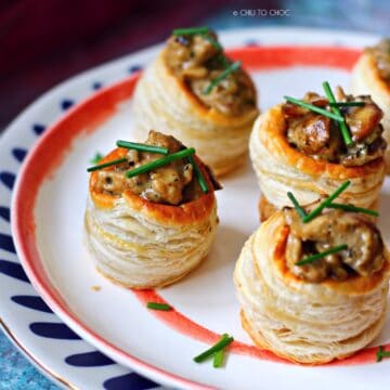 Group of chicken and mushroom vol au vent on a stack of plates.