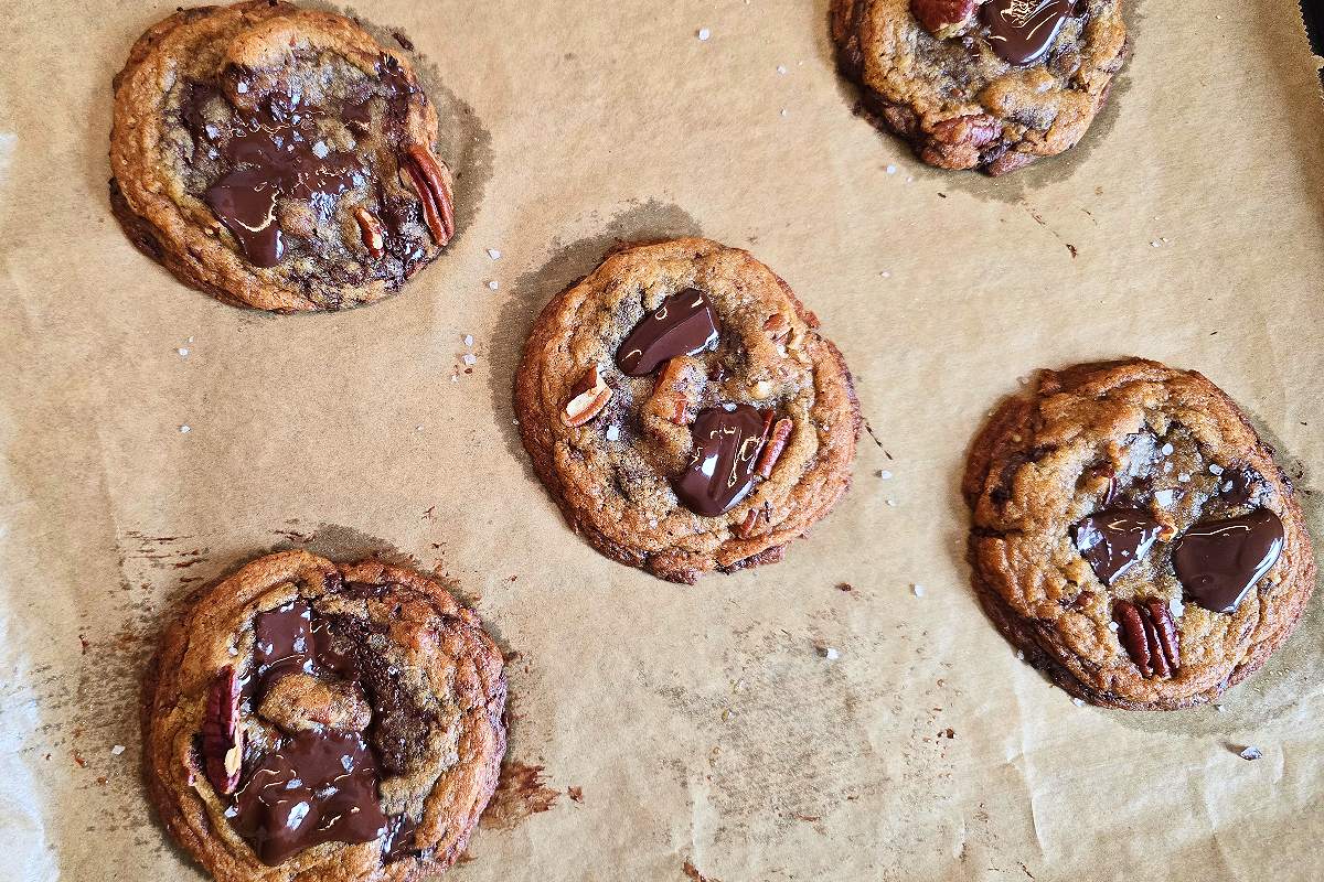 Baked chocolate pecan cookies on a parchment paper.