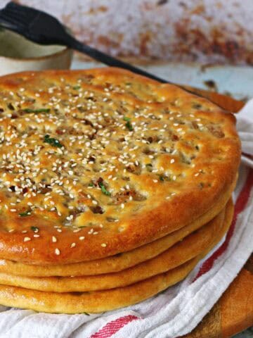 A stack of keema naan on a white fabric and wooden board underneath.
