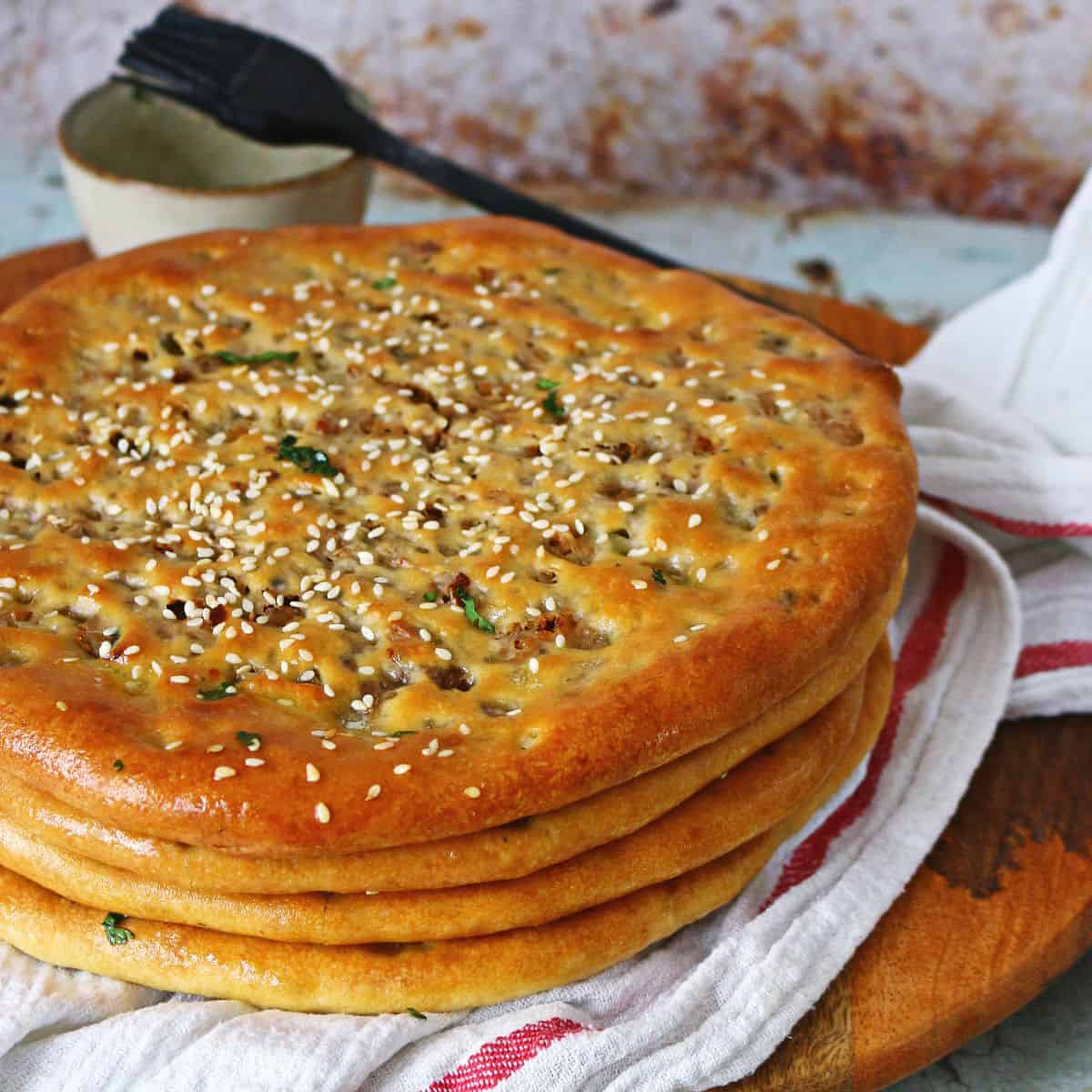 A stack of keema naan on a white fabric and wooden board underneath.