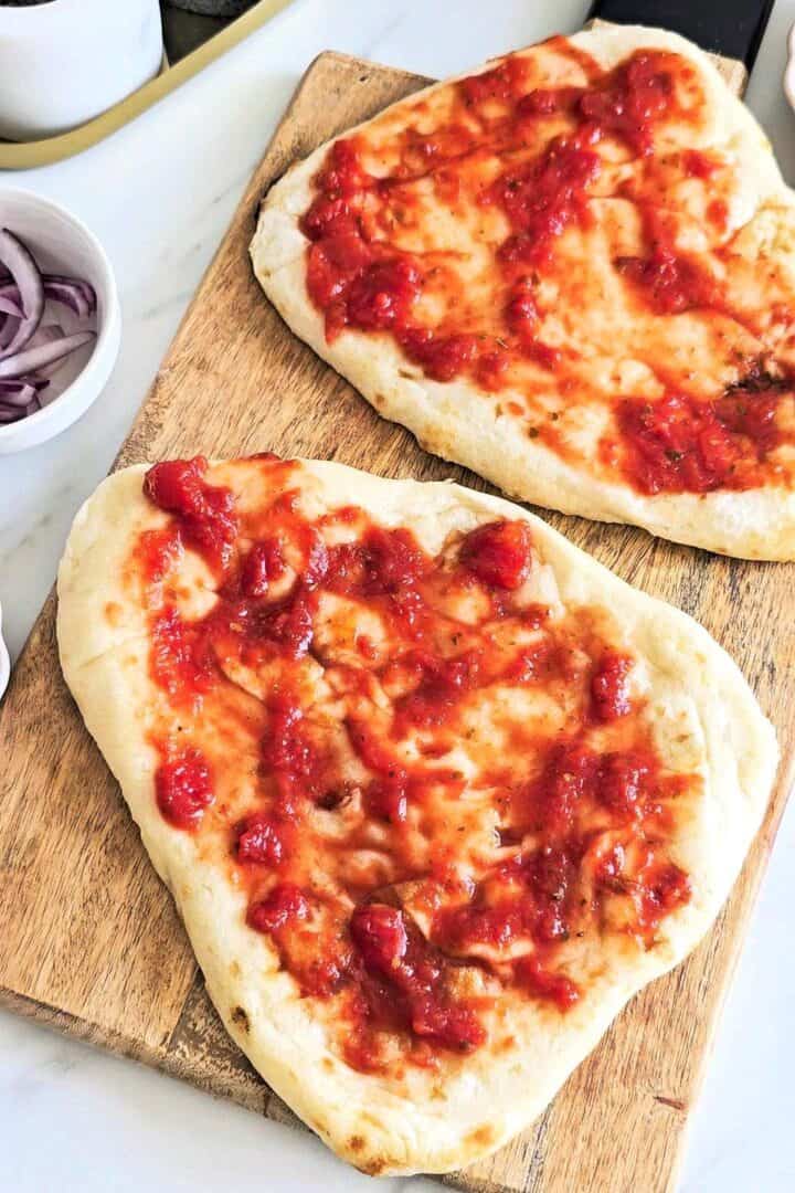 Pizza sauce smeared on flatbread pizza.