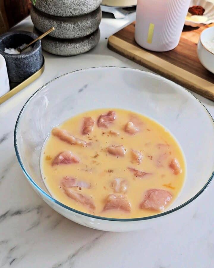 Raw chicken in a bowl of pickle marinade.