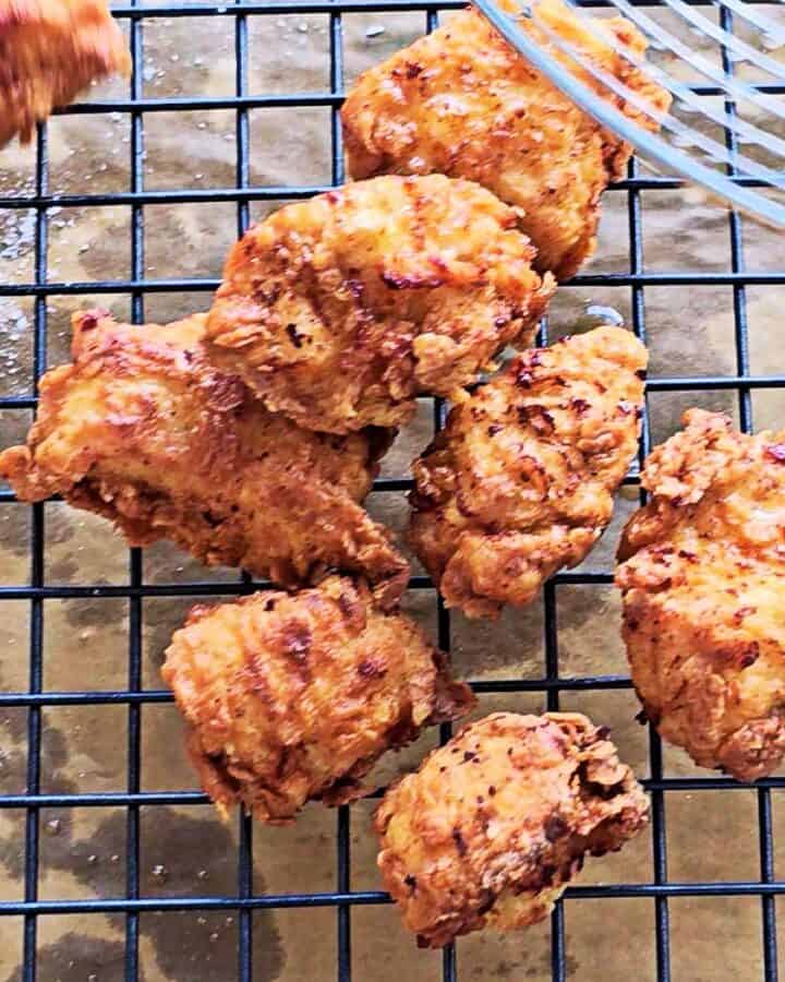 Fried crispy chicken pieces on a wire rack.