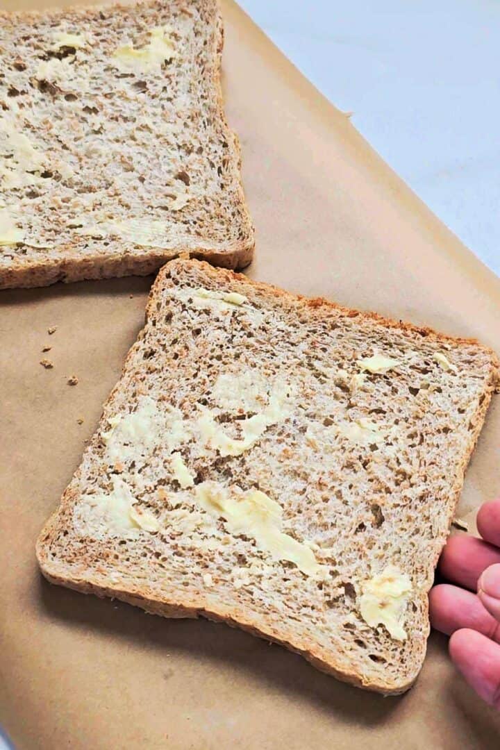 Two buttered slices of toast on a parchment paper.