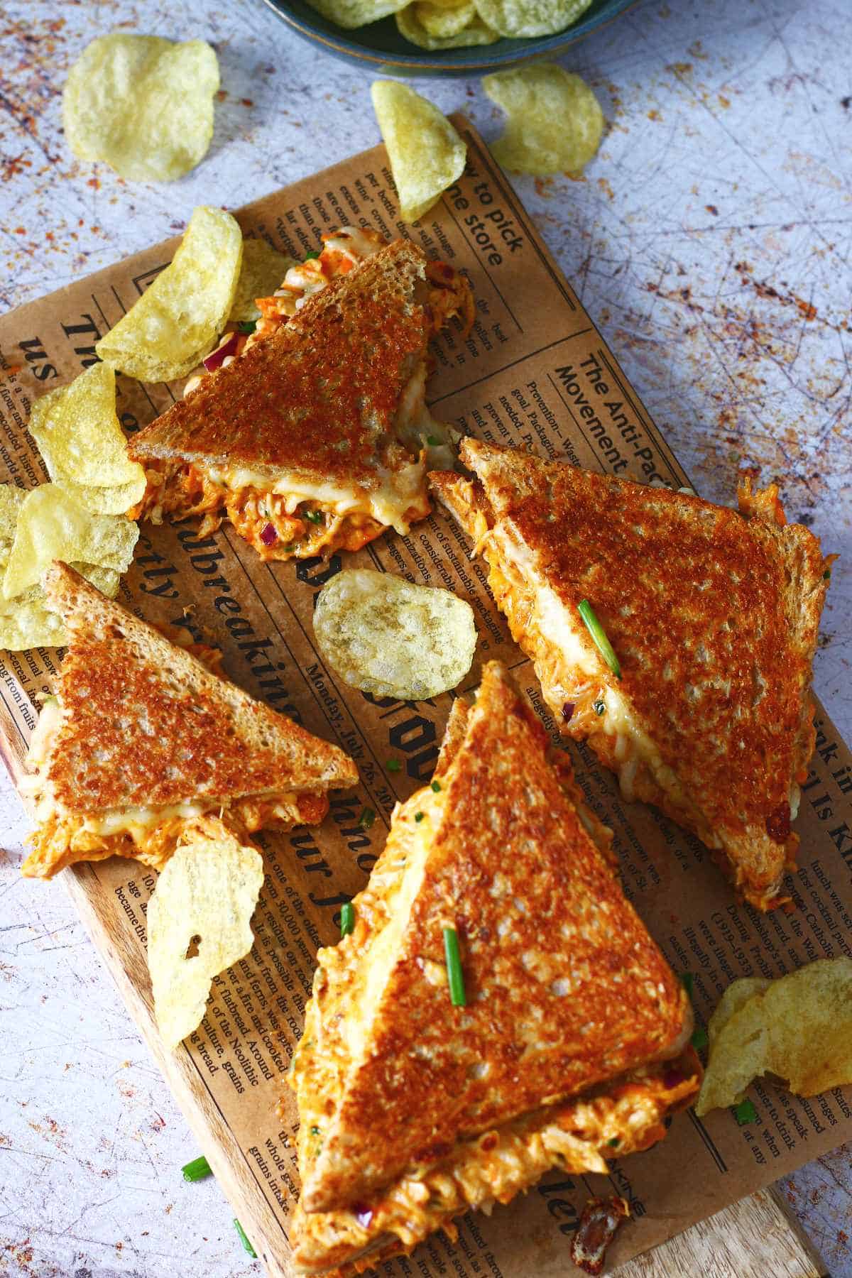 Chicken melt triangles laid out on a wooden board lined with brown paper.