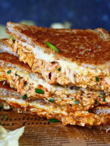 A stack of sliced chicken melt triangles on a parchment paper.