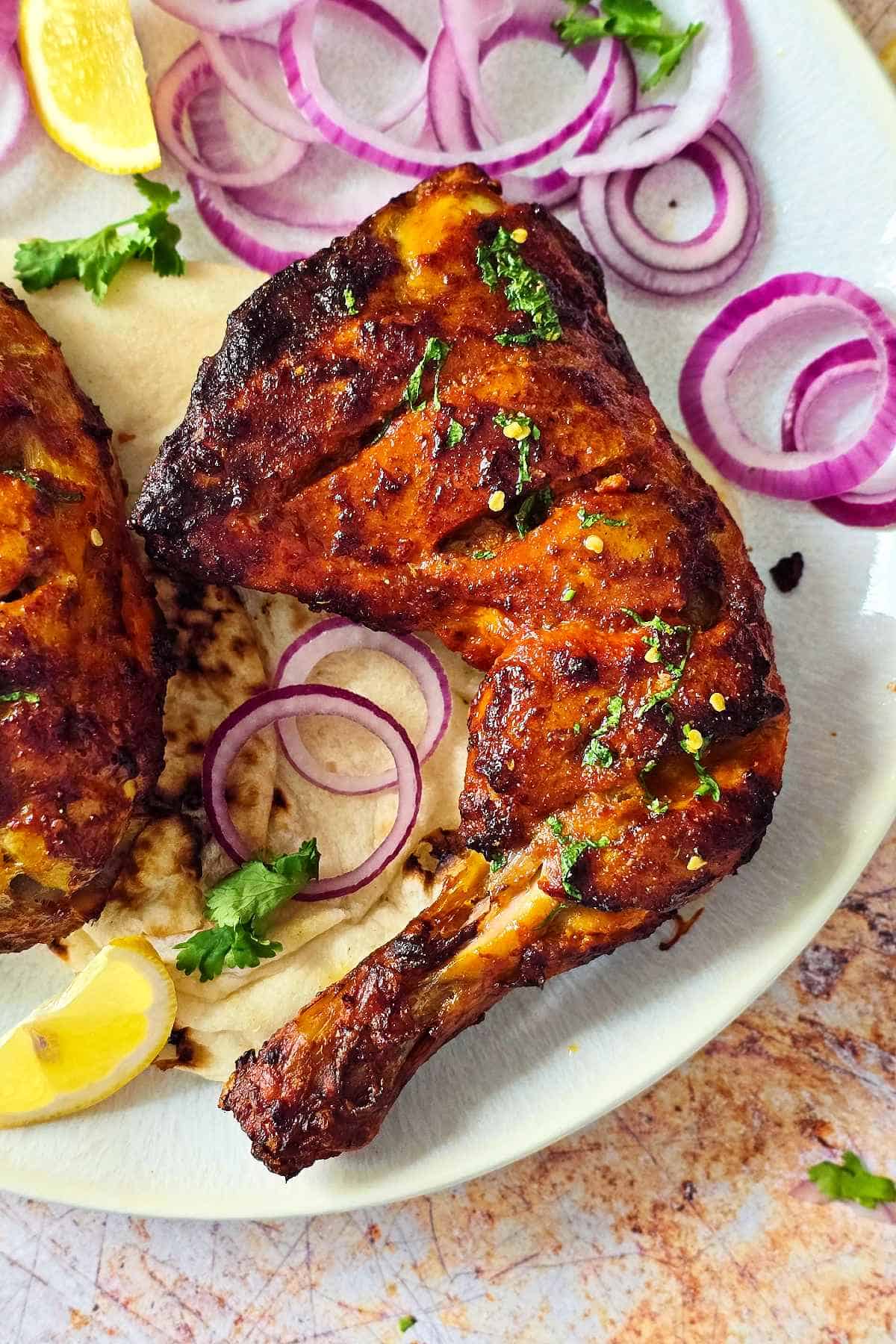 Close up of a tandoori chicken leg quarter.