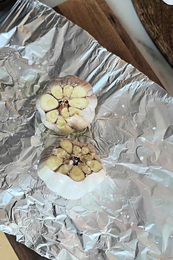 Sliced garlic heads on foil sprinkled with salt before roasting.
