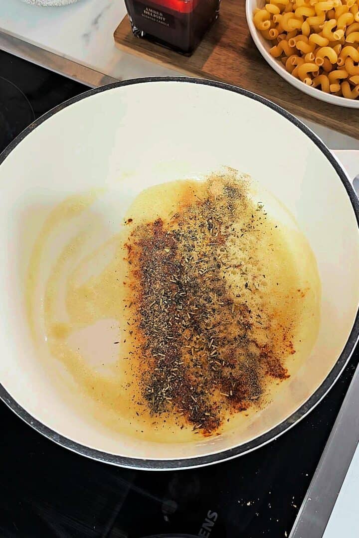 Butter melted in a saucepan with spices like paprika and dried herbs being sautรฉed.