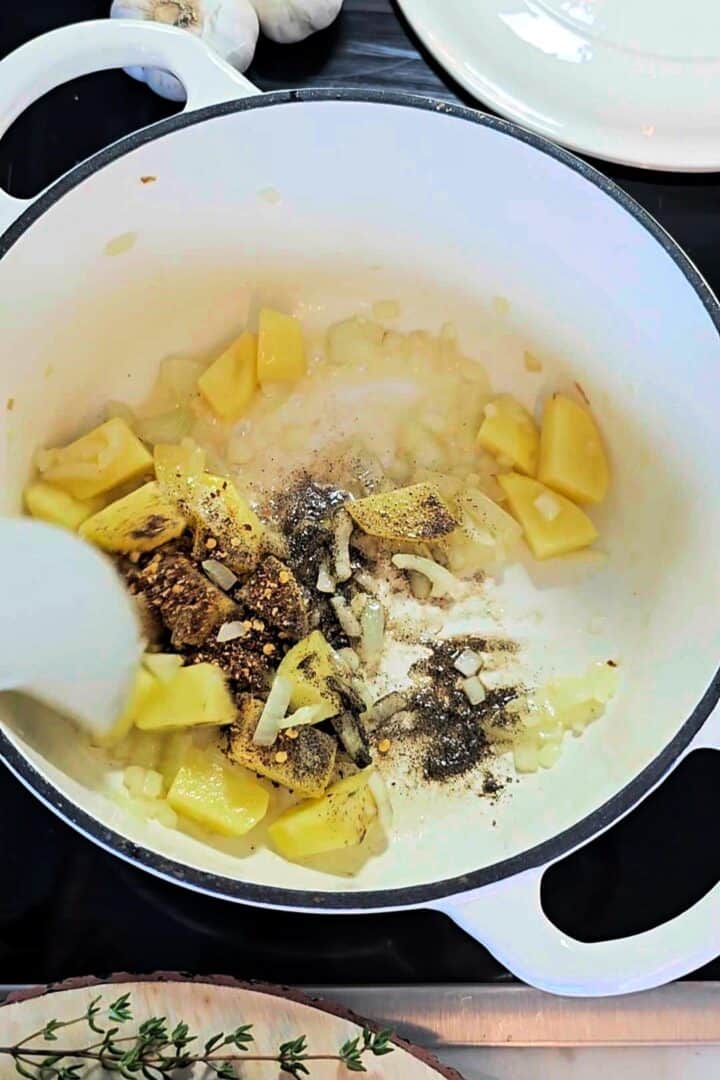 Diced potatoes and onions being sautรฉed with spices in a pot.