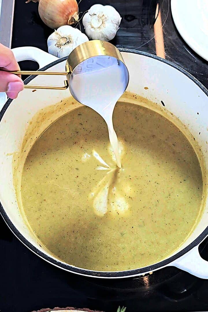 Heavy cream being poured into the blended soup.