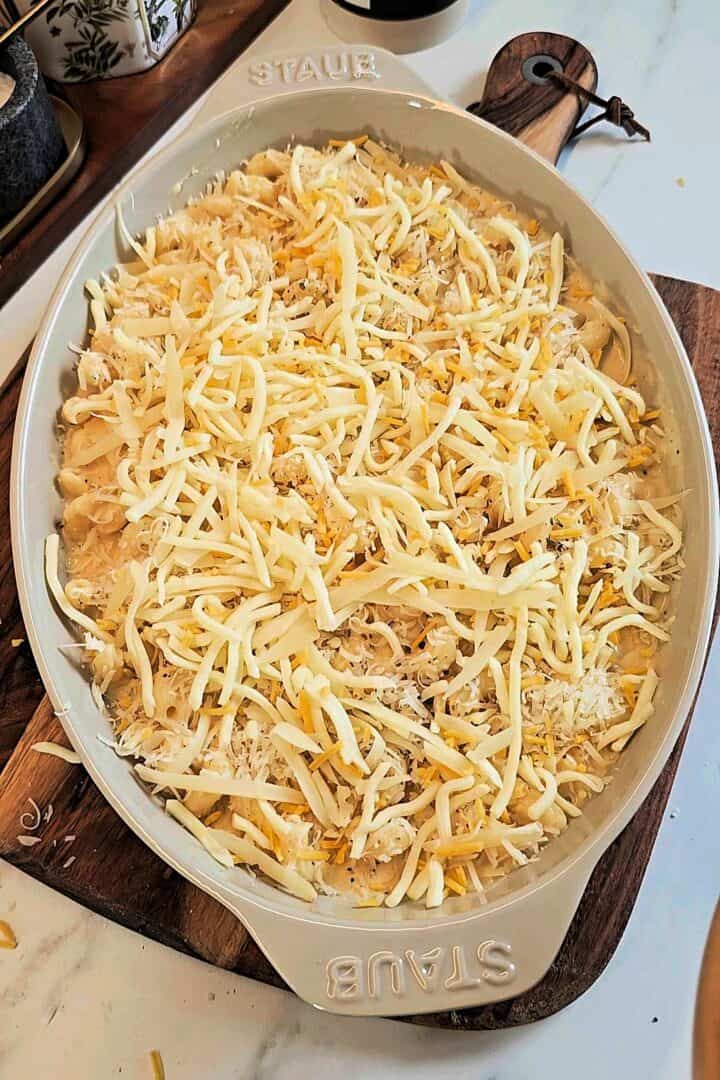 Mac and cheese in the baking dish topped with a final layer of shredded cheese.