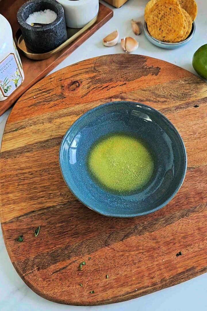 Melted butter in a microwave-safe bowl placed on a wooden board.