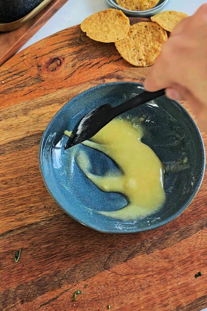 Butter and flour being mixed together in a bowl to form a smooth base for cheese sauce.