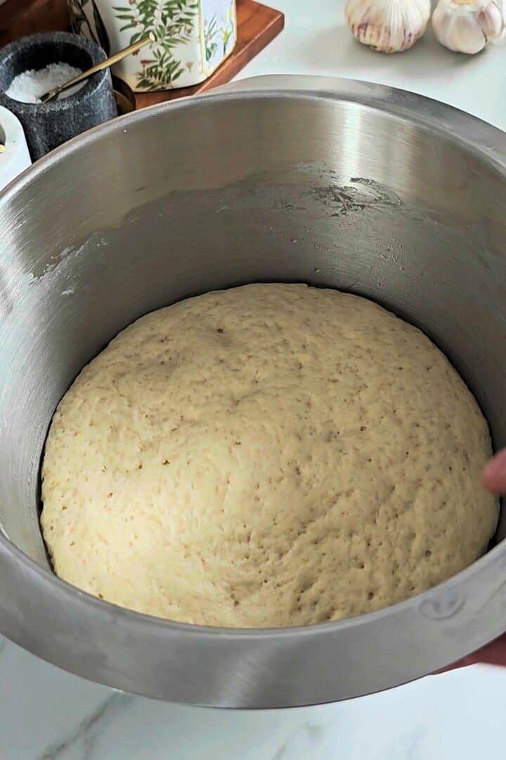 Smooth dough filling a large metal bowl.