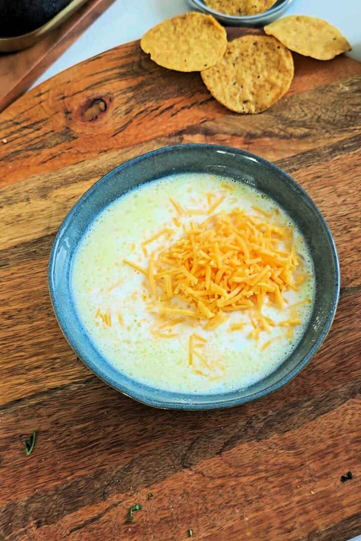 Milk and shredded cheddar cheese added to the bowl before microwaving for cheese sauce.