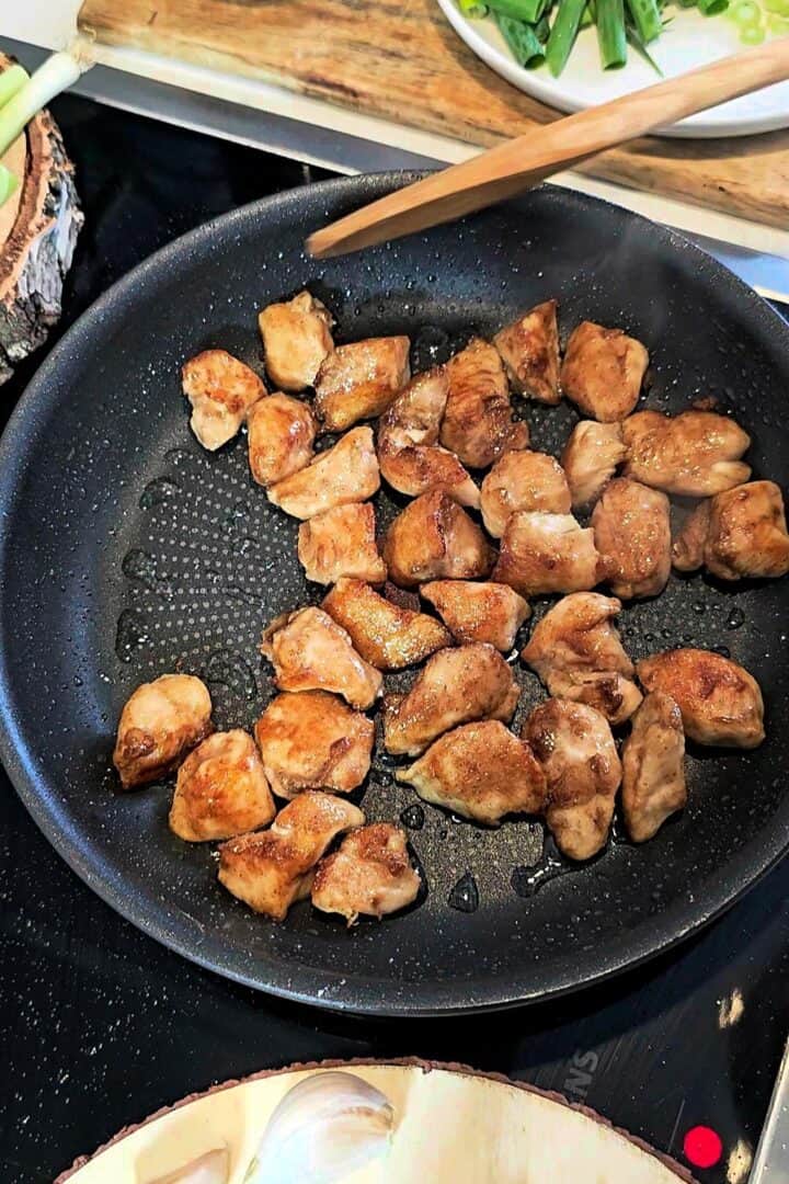 Pan-fried chicken pieces cooking in a skillet until golden brown.