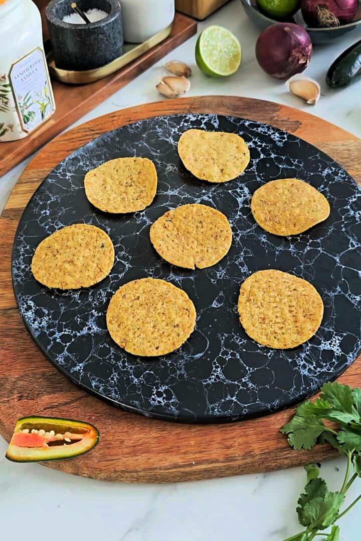 Round tortilla chips arranged on a serving plate, ready for topping.