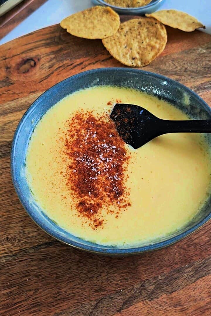 Cheese sauce seasoned with salt and smoked paprika in a bowl.