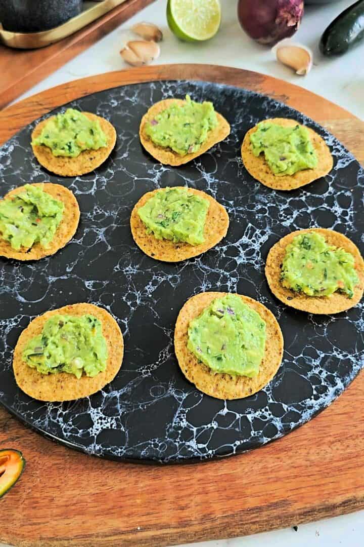 Tortilla chips topped with spoonfuls of fresh guacamole.
