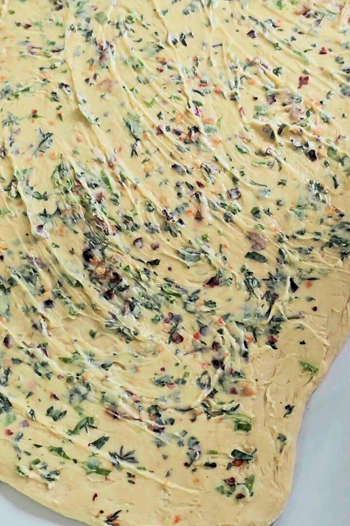 Garlic herb butter spread evenly over rolled dough.