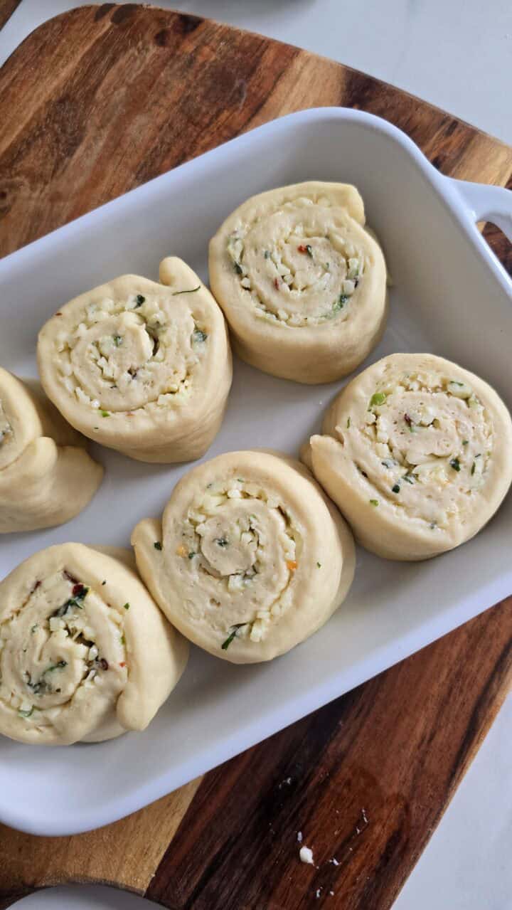 Unbaked spiral rolls arranged in a white baking dish.
