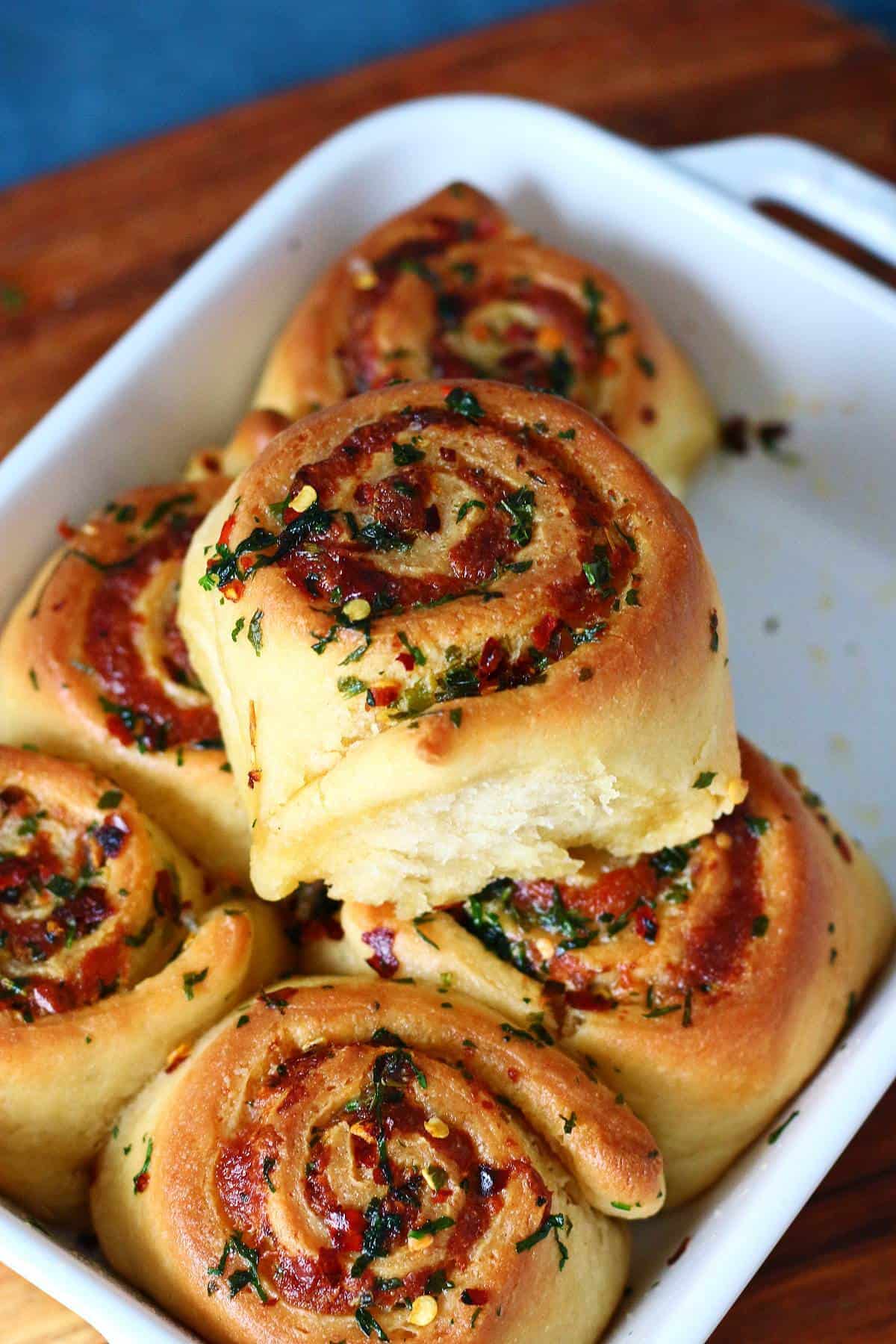 Stacked baked spiral rolls in a white baking dish.