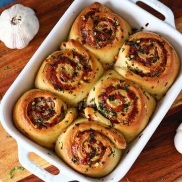 Top-down view of baked cheesy roasted garlic rolls in a baking dish.