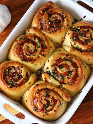 Top-down view of baked cheesy roasted garlic rolls in a baking dish.