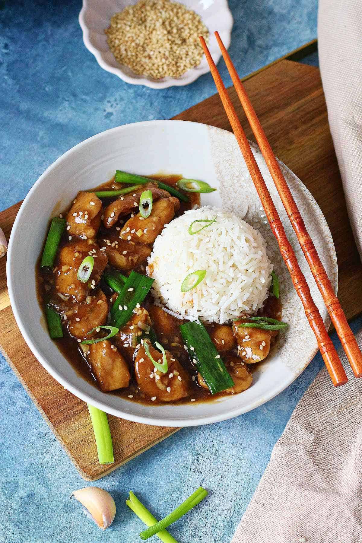 Overhead view of Chinese chicken with garlic sauce and a mound of white rice in a bowl.
