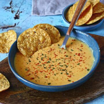 Easy microwave cheese sauce served with tortilla chips on a wooden board.