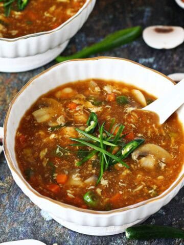 Bowl of 19b soup garnished with sliced green chilies and spring onions.