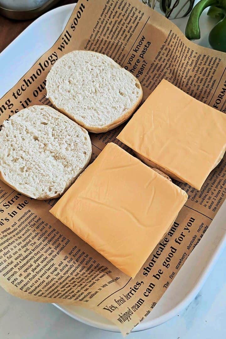 Slider buns cut in half with yellow cheese slices on the bottom buns.