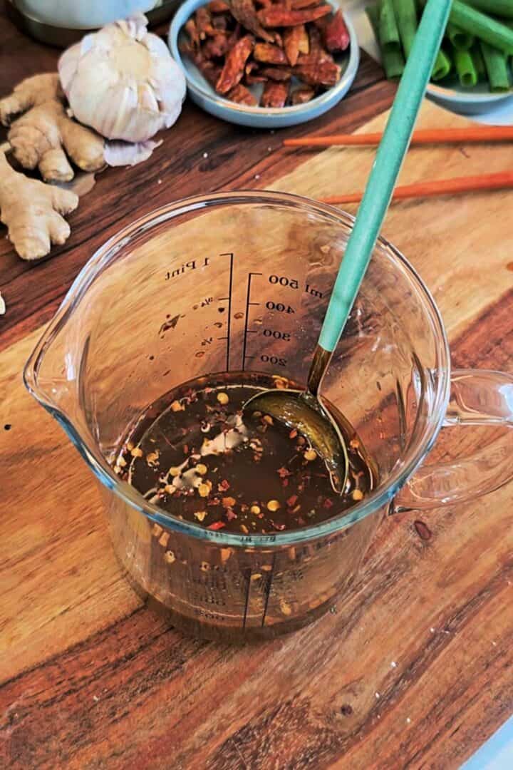 Mixed kung pao sauce in a glass measuring cup.