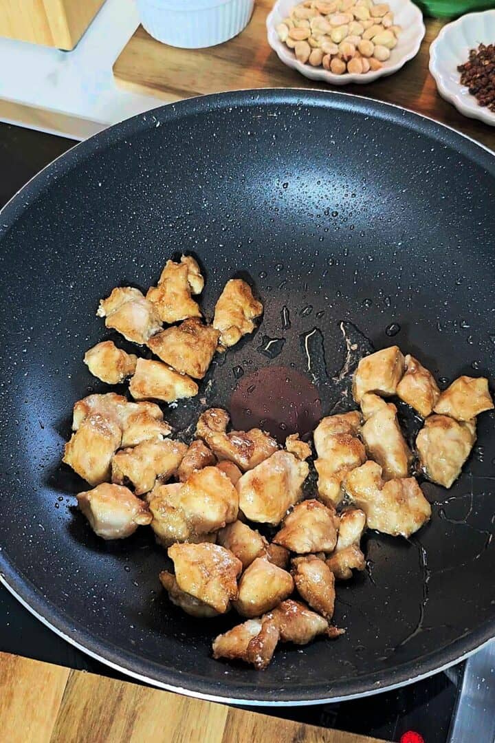 Chicken pieces frying in a hot pan.