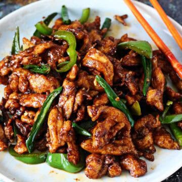 Chinese Chicken Chili Dry served on a white plate with green chilies and bell pepper.