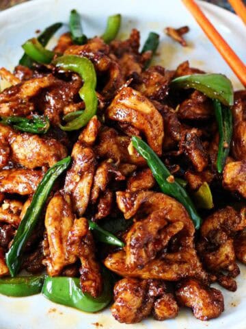 Chinese Chicken Chili Dry served on a white plate with green chilies and bell pepper.