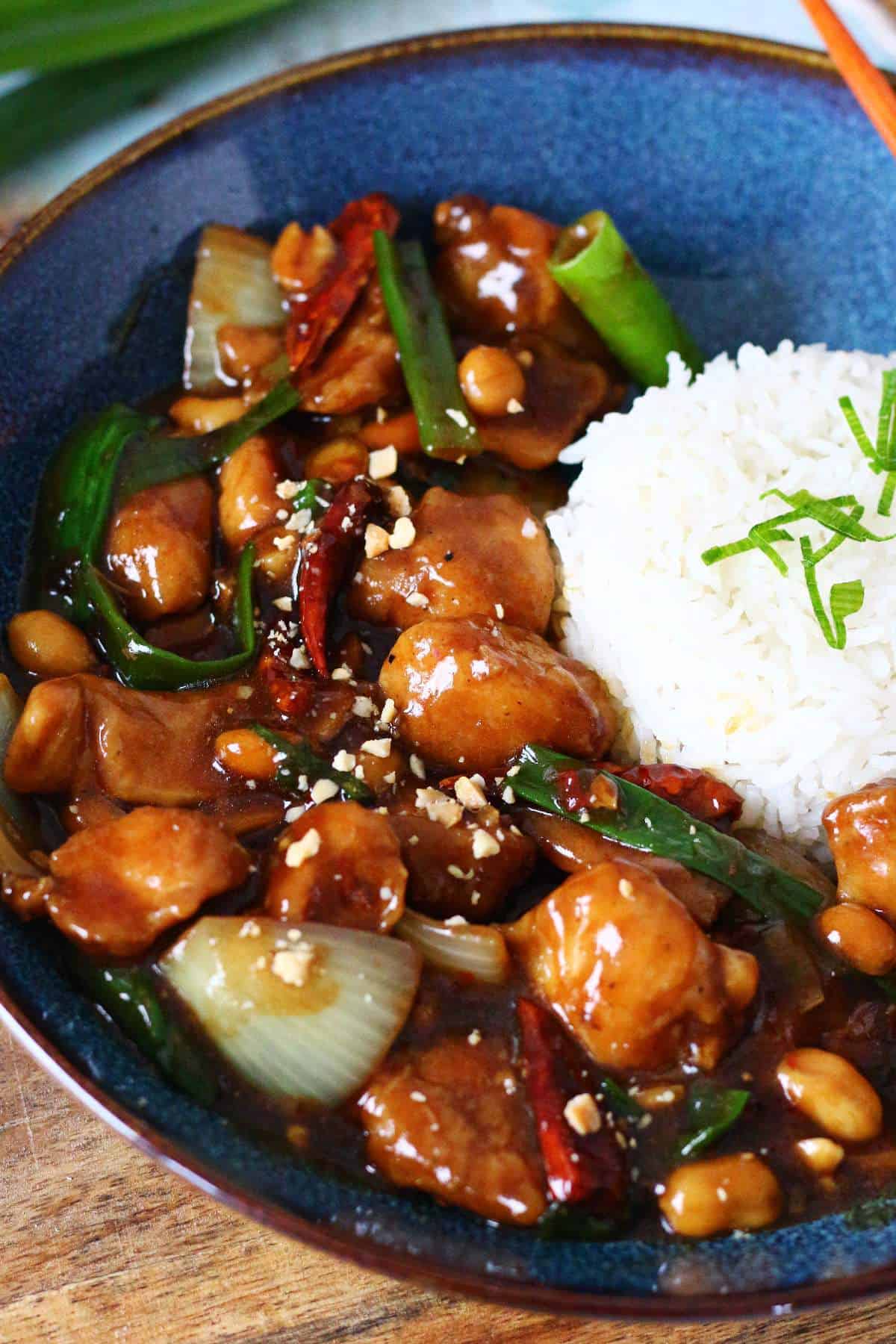 Close-up of Kung Pao Chicken with juicy chicken pieces, toasted peanuts, dried red chilies, and a glossy Sichuan-style sauce.