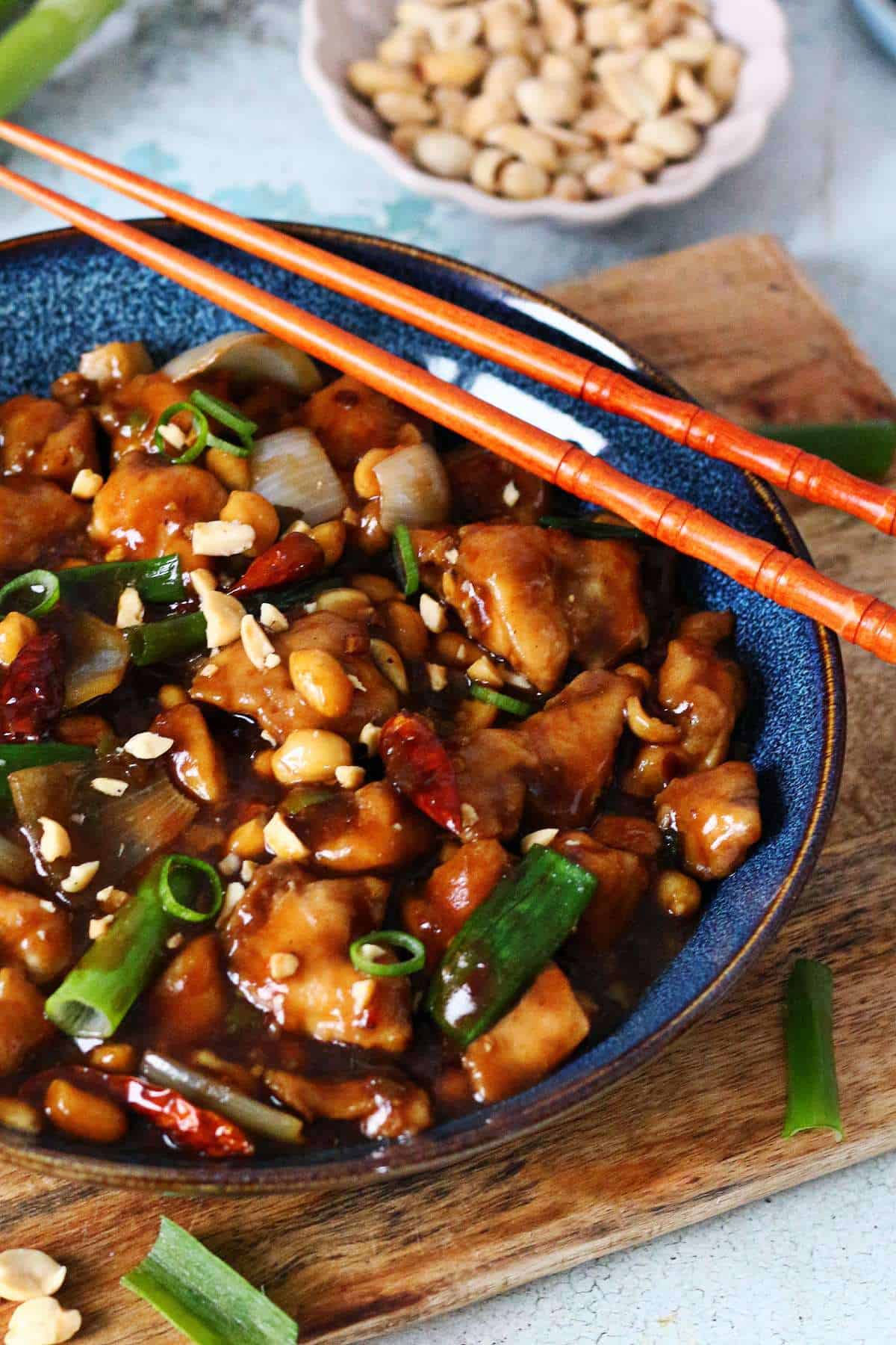 Sichuan-style Kung Pao Chicken served in a shallow plate with chicken, peanuts, scallions, and dried red chilies.