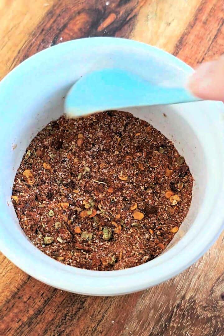 A bowl filled with mixed spices being stirred with a spoon.