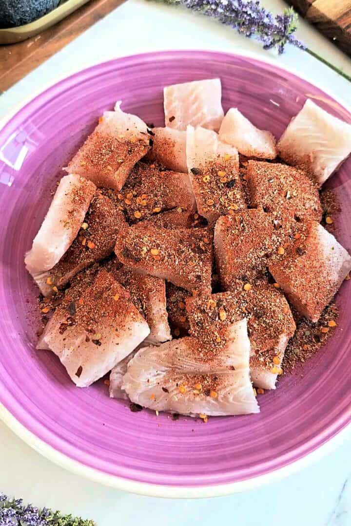 Raw fish pieces in a bowl coated with spices.