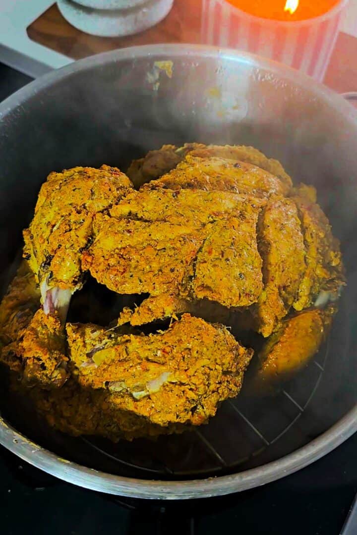 Marinated whole chicken placed on a rack inside a pot for steaming.