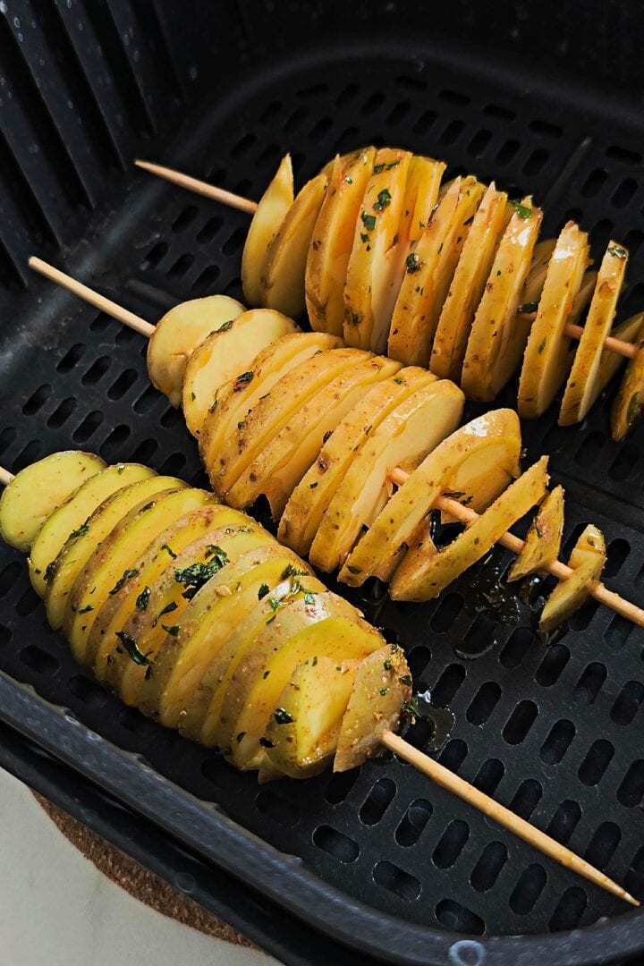 Seasoned spiral potatoes placed in an air fryer basket before cooking.