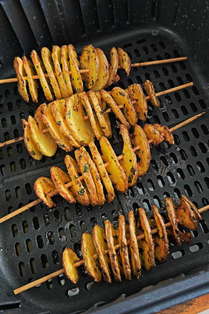 Cooked spiral potatoes in an air fryer basket with golden crispy edges.